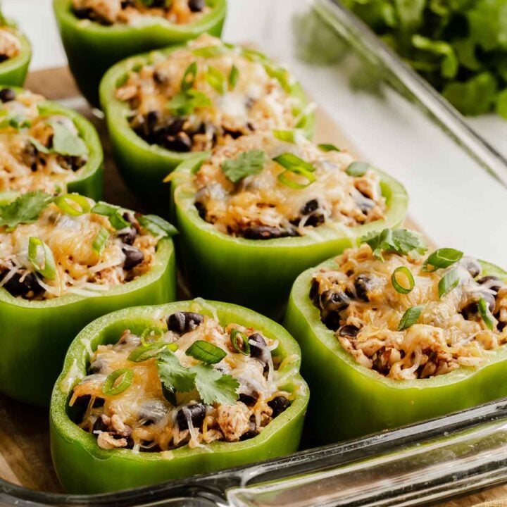 Glass dish of green bell peppers stuffed with beans, rice and cheese.