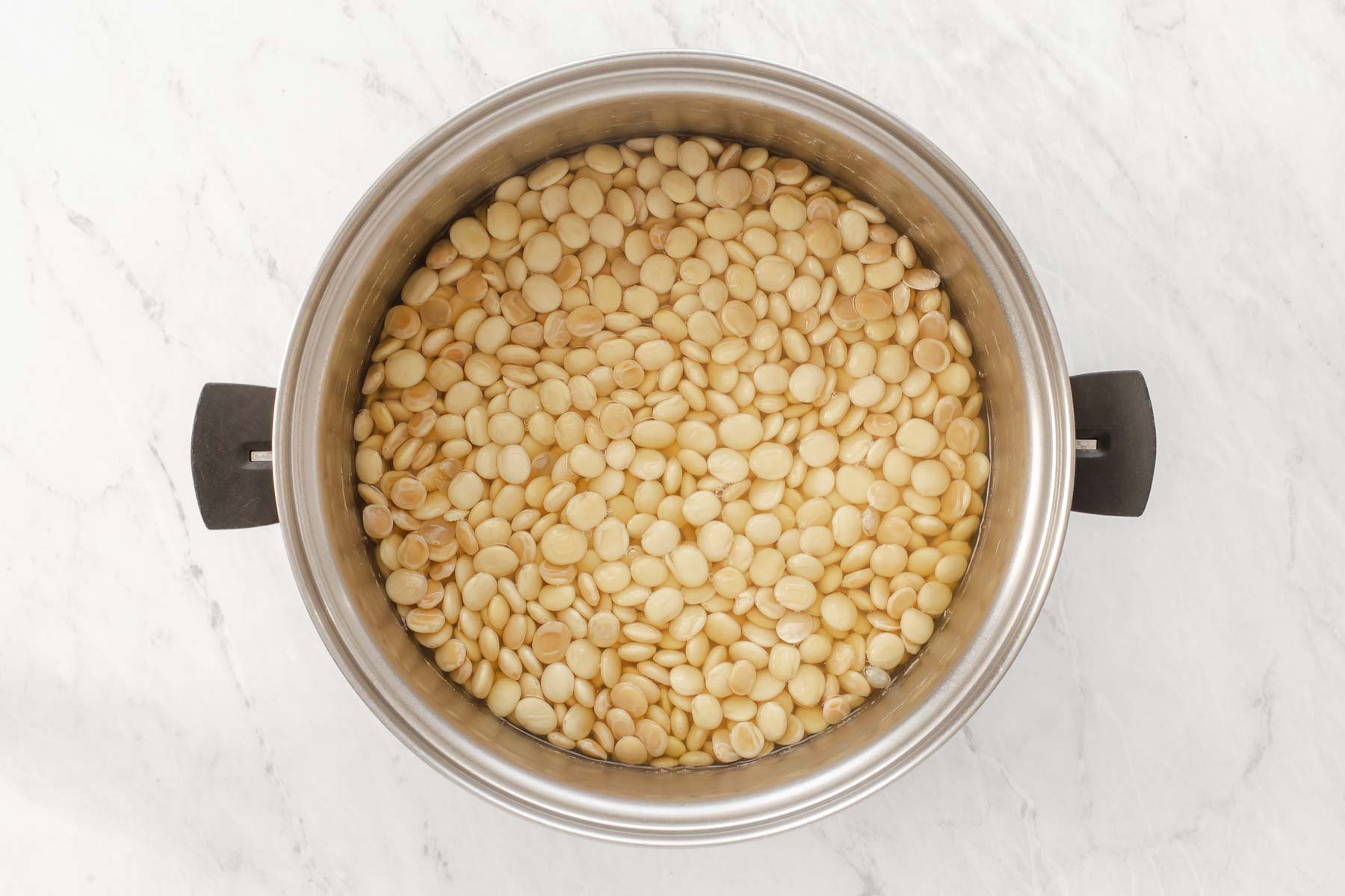 Cooking white legumes in silver pot.