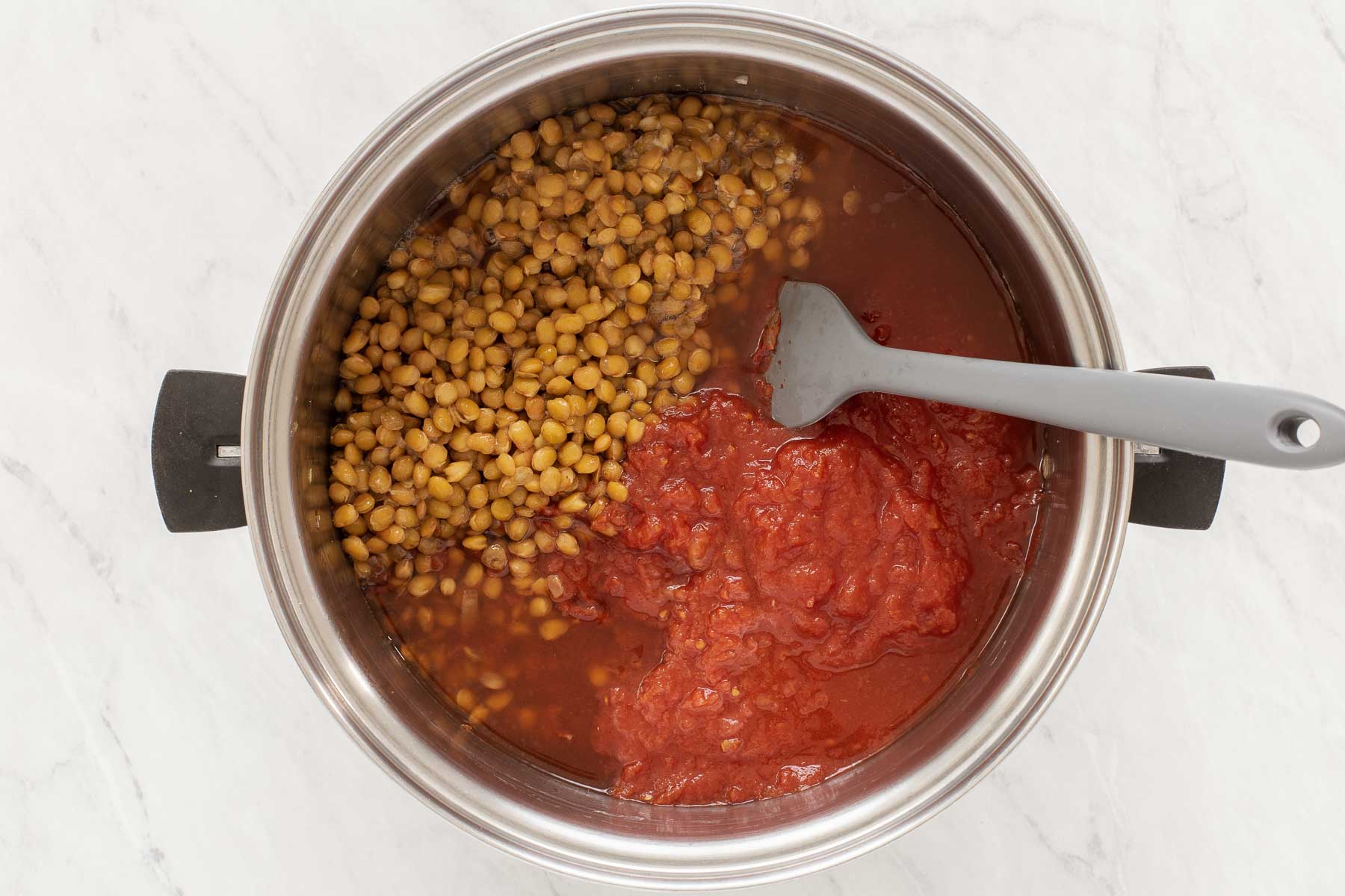 Silver pot with tomato sauce and lentils.