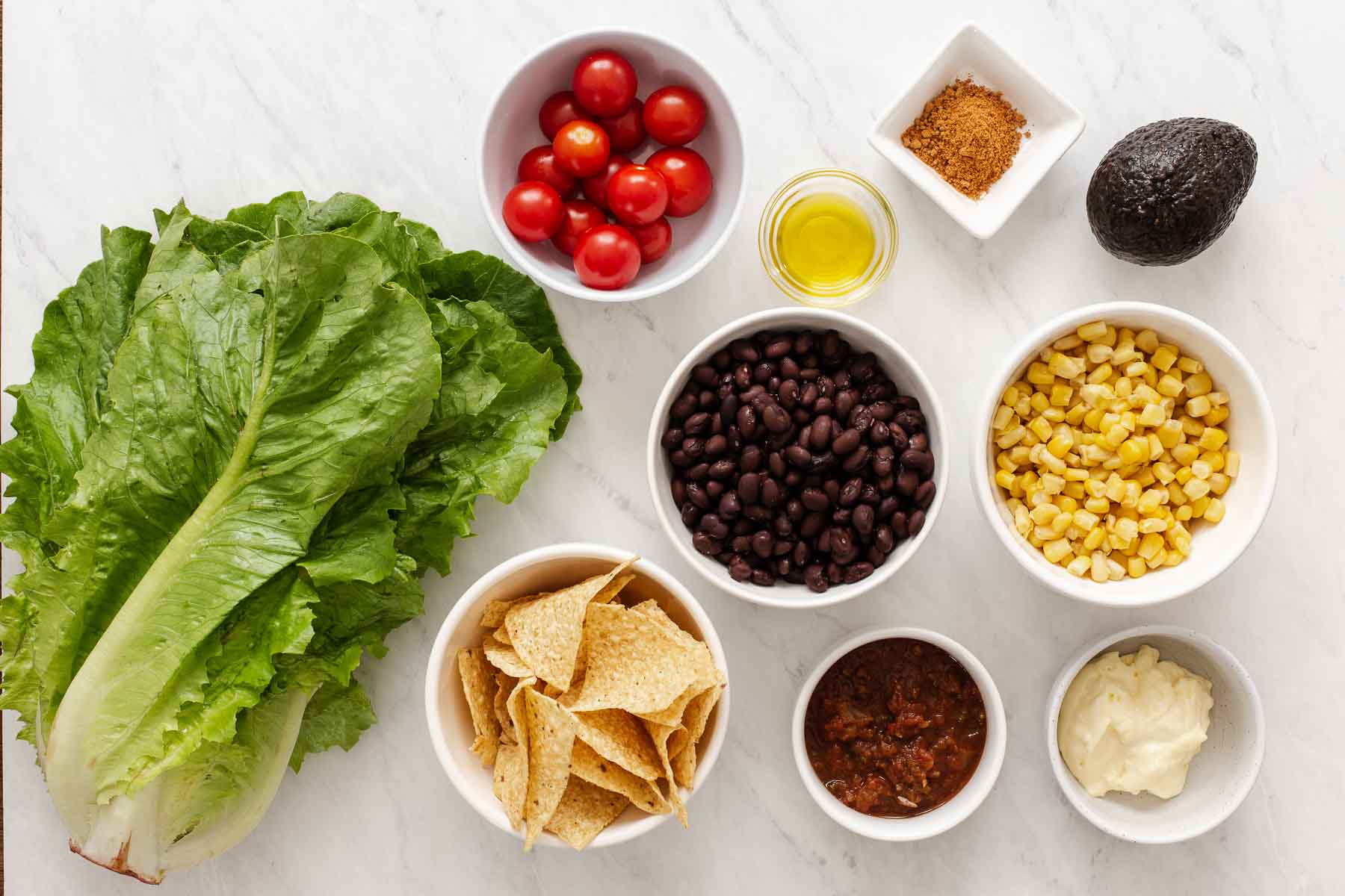 Small bowls of black beans, tomatoes, corn, lettuce and tortilla chips.