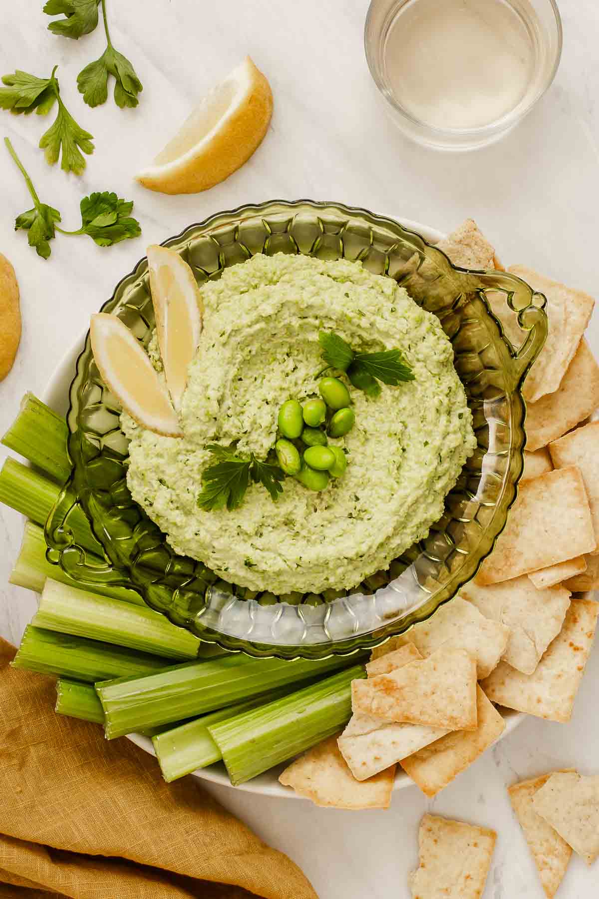 Overhead shot of edamame hummus surrounded by celery and pita chips.