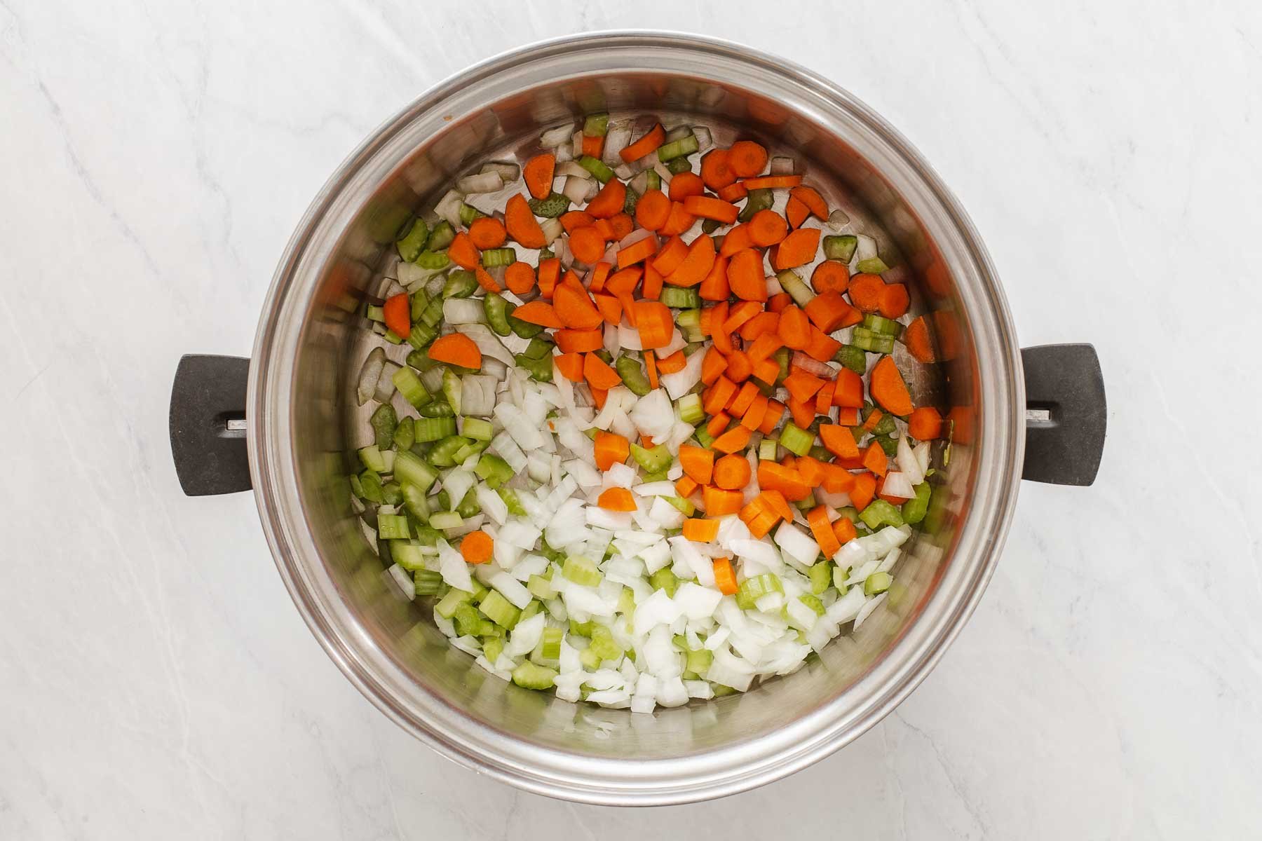Diced carrot, celery and onion in a silver pot.