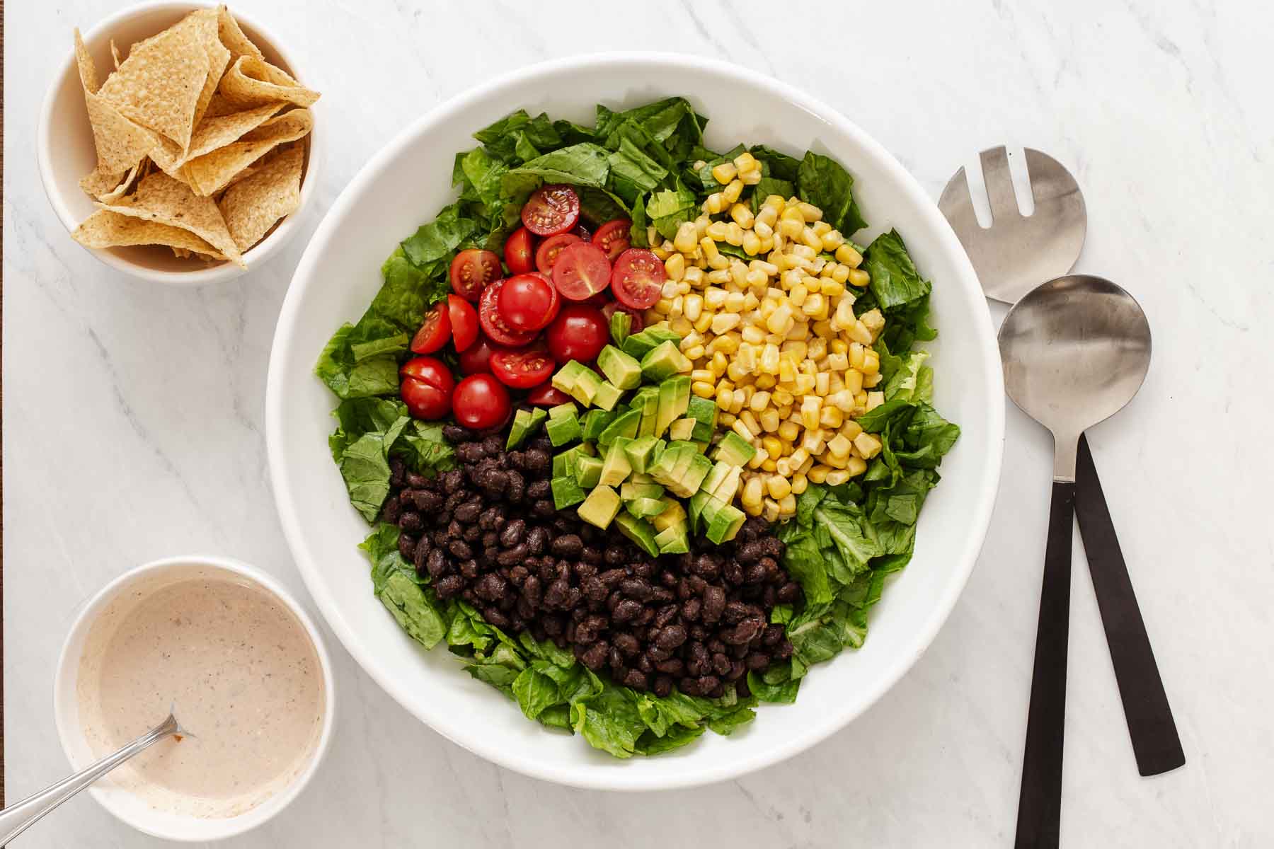 Overhead shot of salad bowl with piles of corn, tomatoes and black beans.
