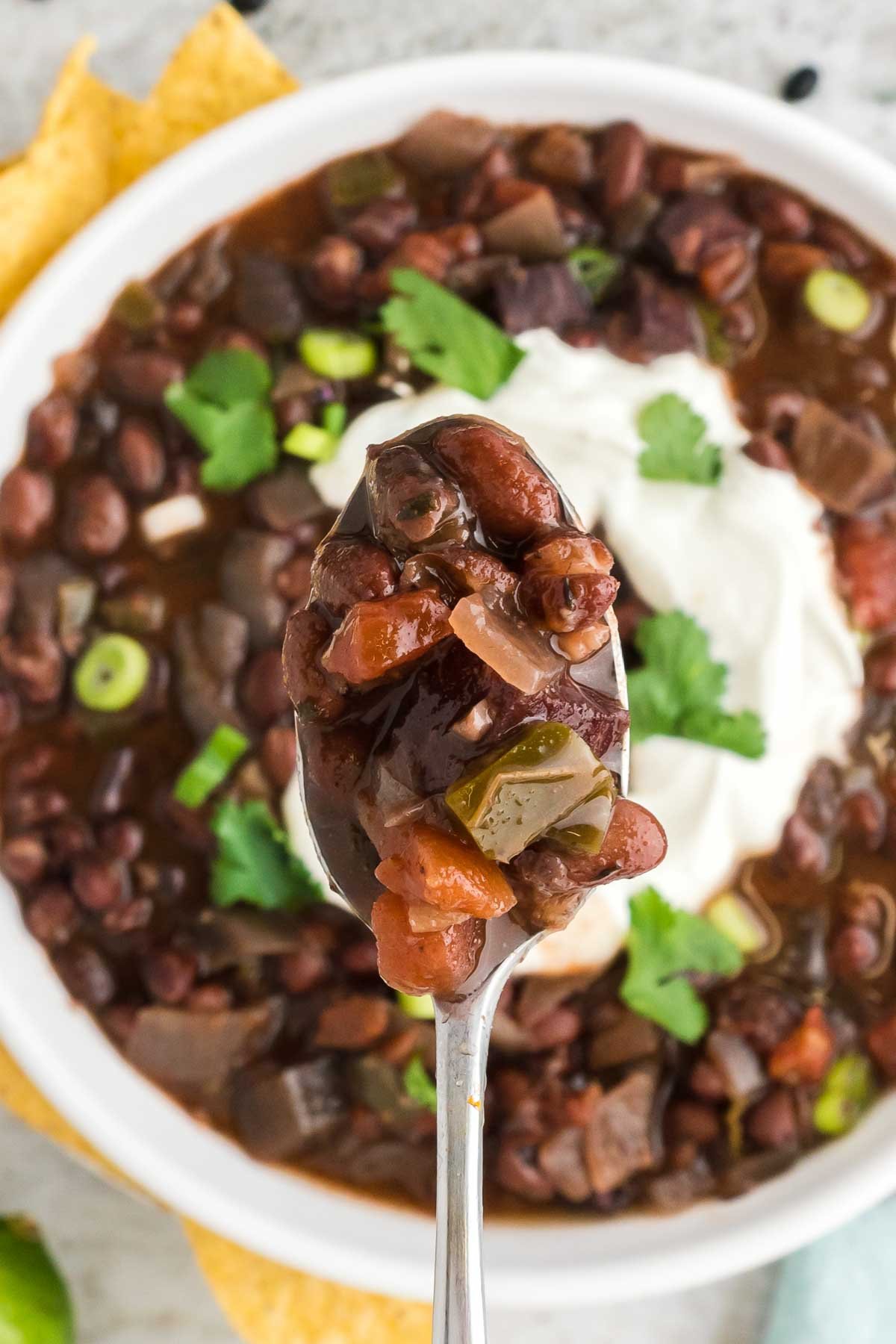 Macro shot of black bean soup with sour cream swirl and spoon.