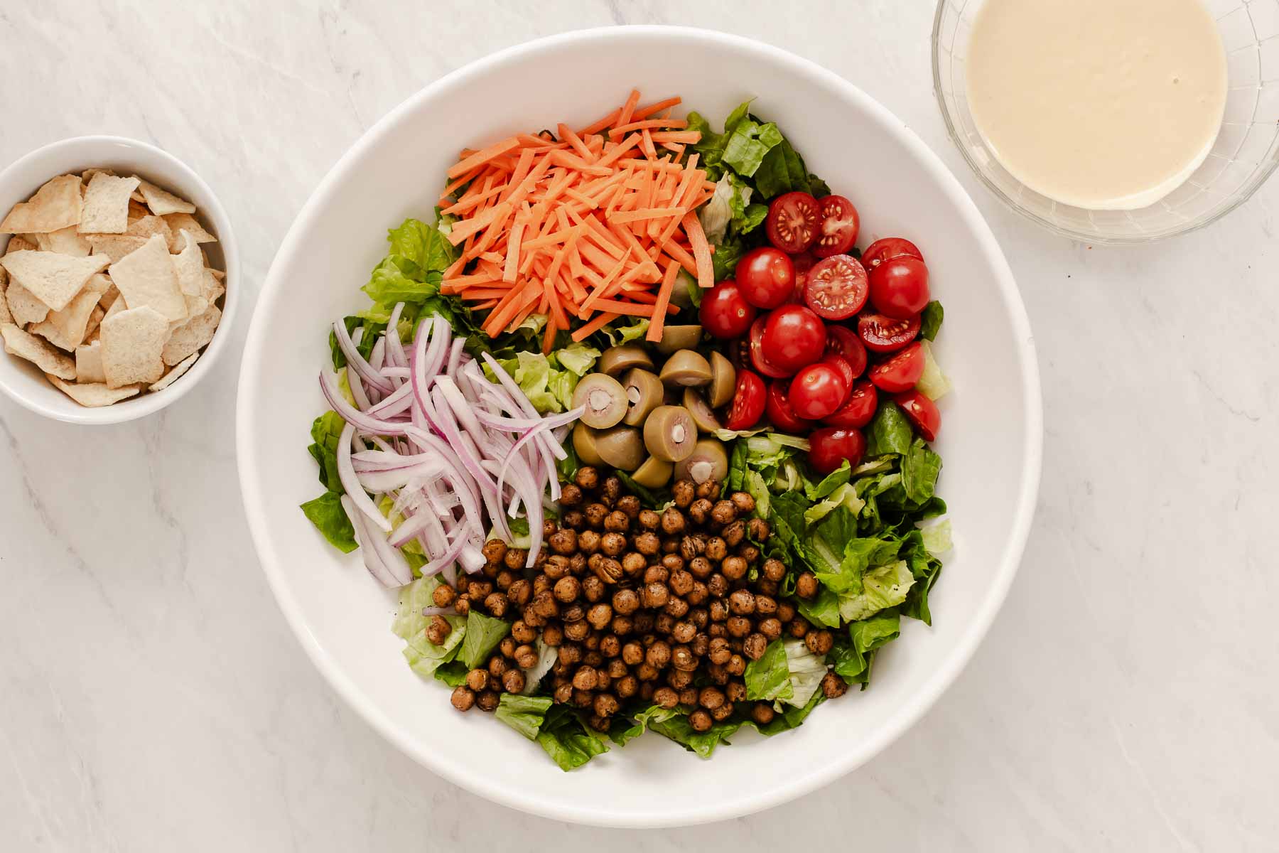 Horizontal image of salad bowl with ingredients grouped on the sides.