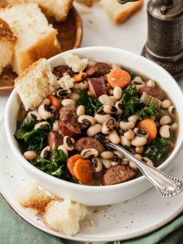 Vertical image of black eyed pea soup with carrots and greens.