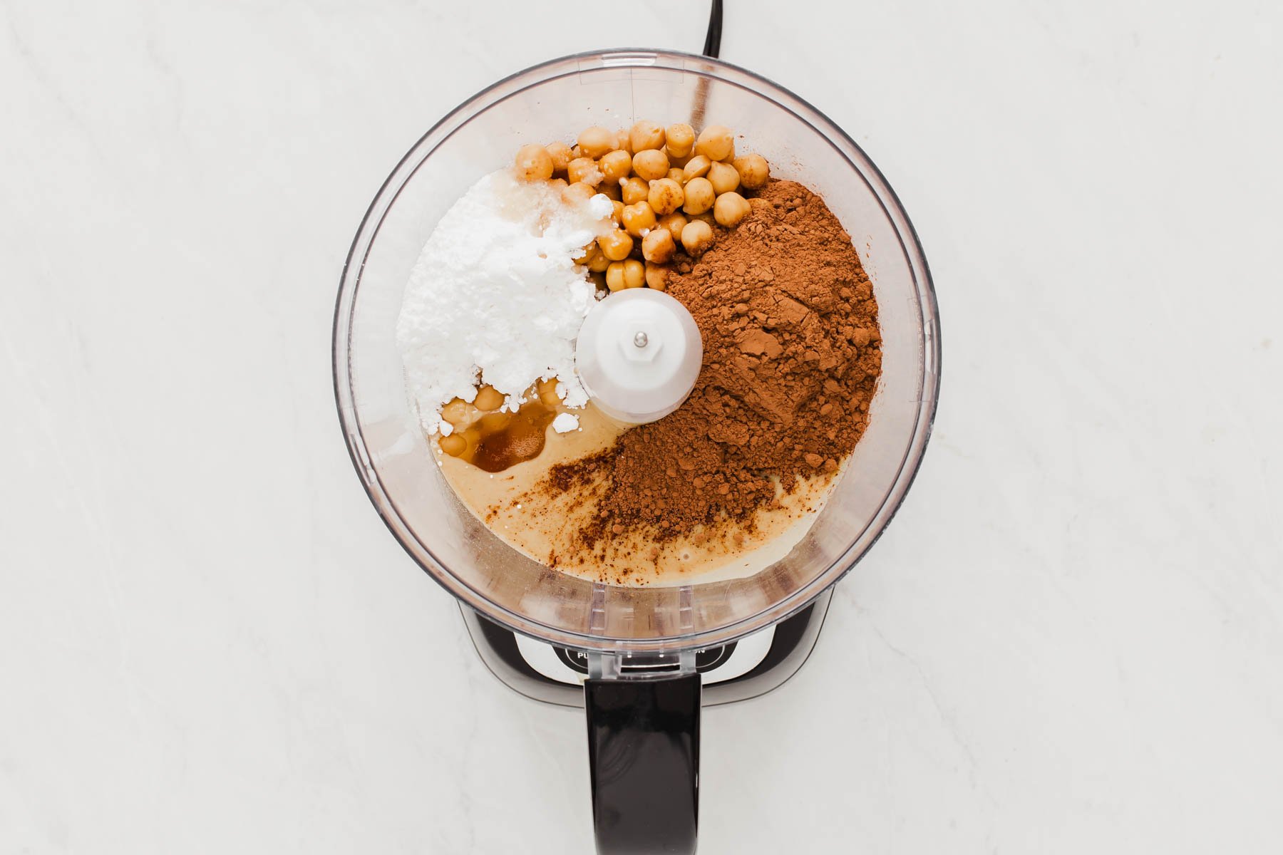 Food processor bowl with chickpeas, cocoa powder and powdered sugar.