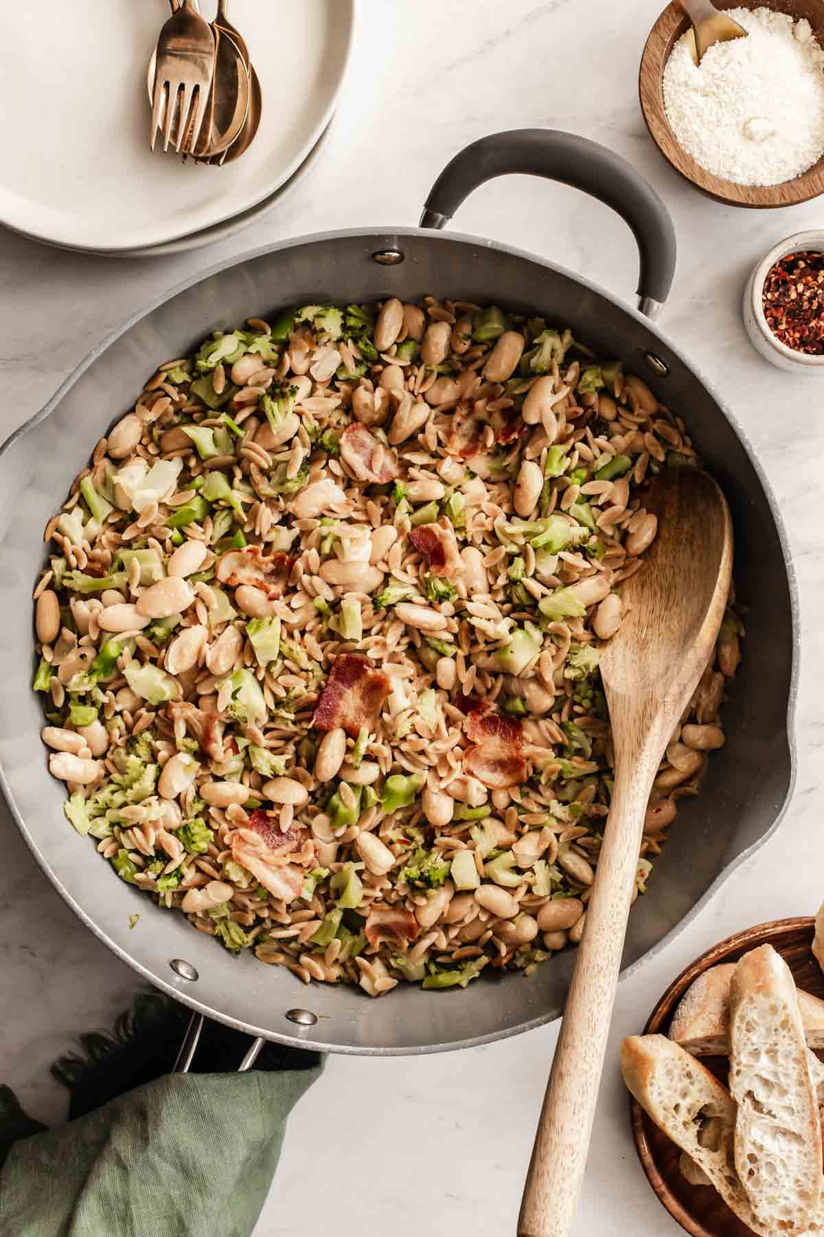 White bean skillet dinner with bacon and broccoli on counter.