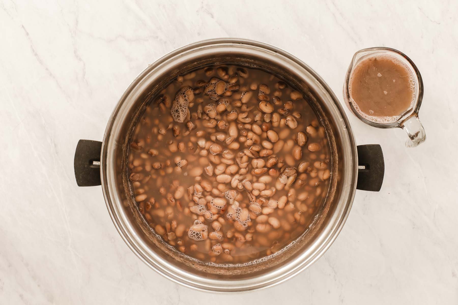 A silver pot of freshly cooked pinto beans.