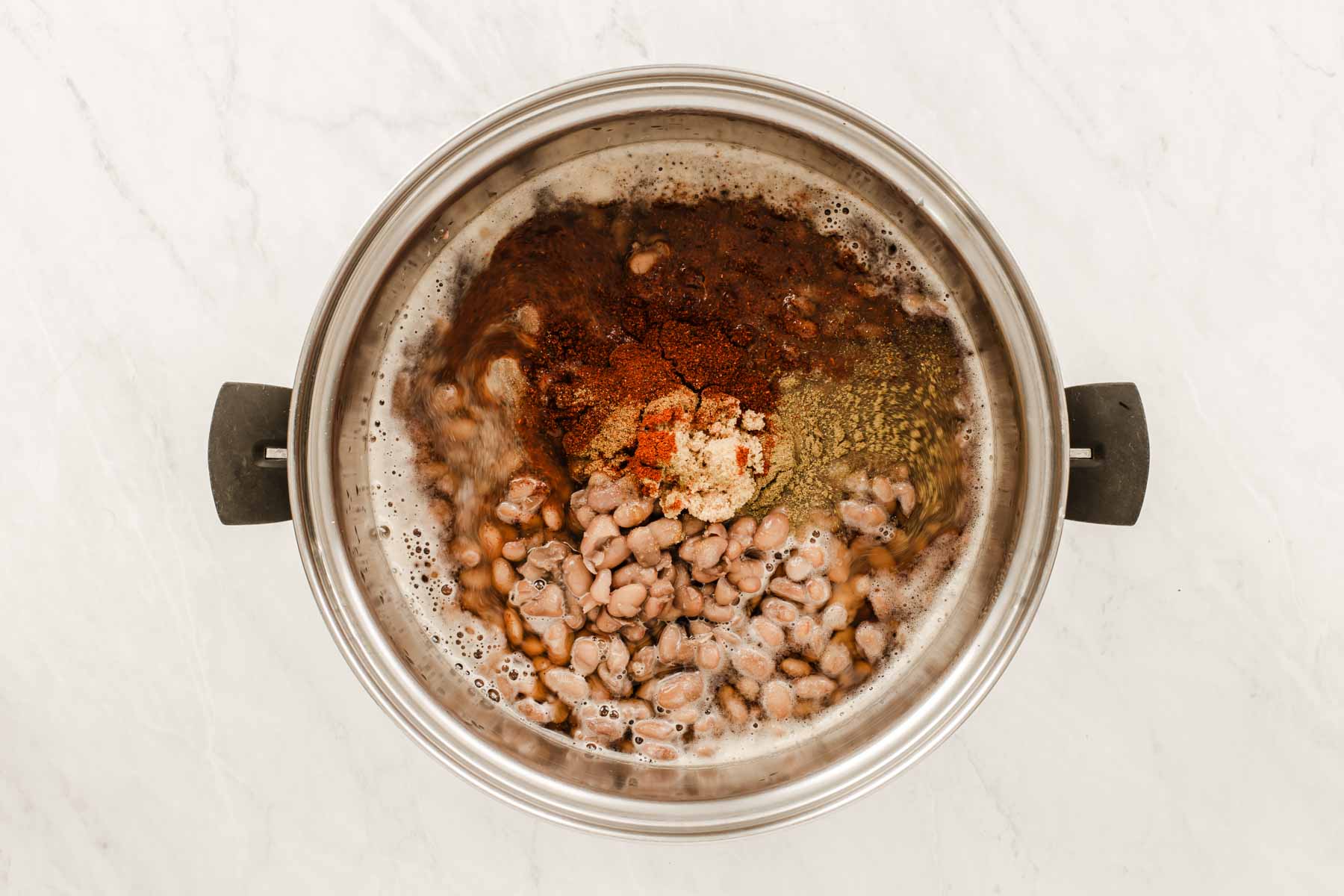 Pot of beans with spices stirred in.