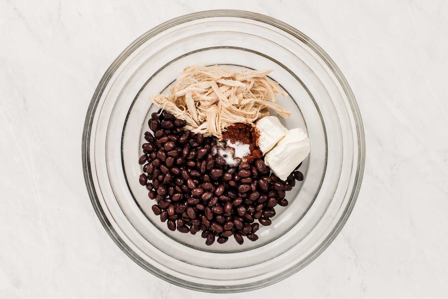 Bowl of black beans, shredded chicken, cream cheese and spices.