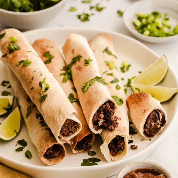 Black bean taquitos on a white plate sprinkled with cilantro.
