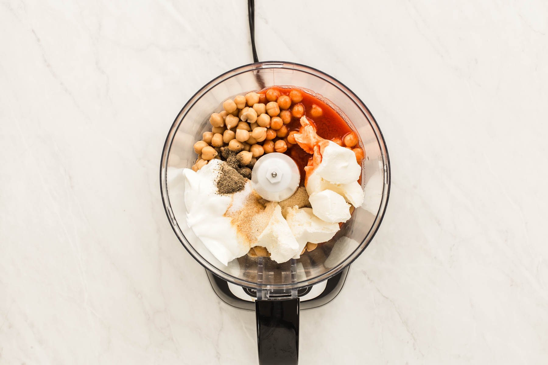Food processor bowl with beans, cream cheese and red sauce.